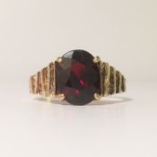 A 9ct gold single stone garnet ring with textured shank, Hall marked Birmingham 1977, size M.