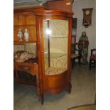 A mahogany corner cabinet with bow front.