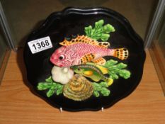 A ceramic wall plaque depicting fish and shell fish.