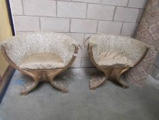 A pair of gilded salon chairs with floral resin bases.