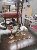 A brass poker in stand, a pair of brass candlesticks and a brass toasting fork.