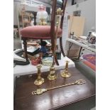 A brass poker in stand, a pair of brass candlesticks and a brass toasting fork.