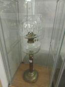 A brass oil lamp with clear glass font and shade.