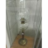 A brass oil lamp with clear glass font and shade.