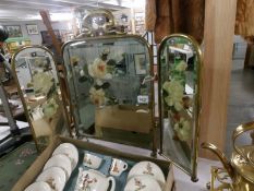 A brass triple fire screen with hand painted mirror insets.