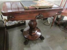 A Victorian mahogany fold over table on pedestal base.