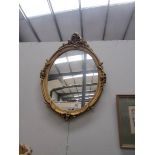 An oval gilt framed mirror.