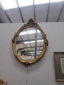 An oval gilt framed mirror.