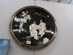 A lacquer and mother of pearl wall plaque depicting 2 Japanese ladies playing a game.