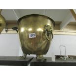 A brass jardiniere with lion head handles and lion paw feet.