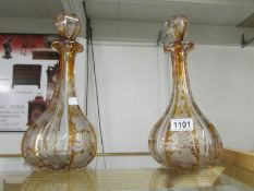 A pair of amber overlaid engraved glass grape scene decanters.