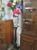 A vase of silk flowers on a pedestal.