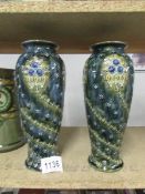 A pair of Doulton Lambet vases in greenish-grey colour with stylised flowers and stems coiling