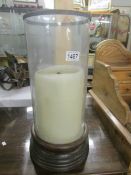 A large glass candle holder with candle.