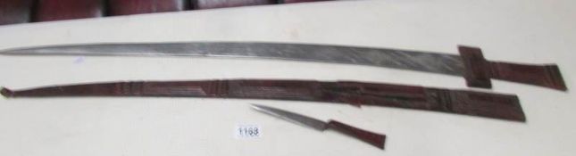 An early 20th century sword with engraved blade and in decorative scabbard with skinning knife.