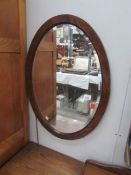 An oak framed oval bevel edged mirror.