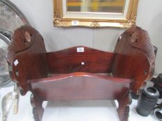 A mahogany dolls cot with carved ends.