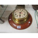 A brass ship's clock on wooden back plate,.