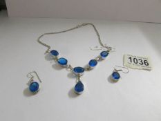 A matching set of silver with blue gemstones necklace and earrings.