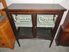 An inlaid display cabinet with Cadbury advertising to doors.