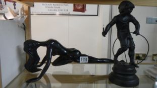 A spelter figure of a boy playing with a hoop together with a posing nude lady figure.