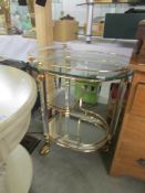A gilded tea trolley with glass trays.