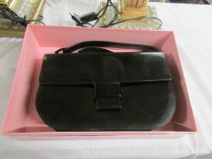 A boxed black patent leather Kurt Geiger handbag with shoulder strap.