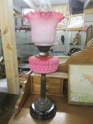 A brass oil lamp with pink glass font and shade (shade is cracked,