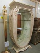 A super Romanesque oval display unit with mirrored back and glass shelves.