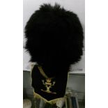 A footguards bearskin helmet with cane framework and brass chin strap together with a Gordon