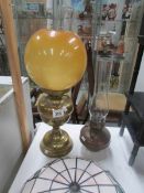 A brass based oil lamp with glass shade and a copper oil lamp font with chimney.