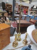 A brass poker in stand, a pair of brass candlesticks and a toasting fork.