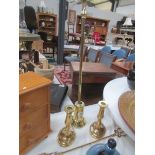 A brass poker in stand, a pair of brass candlesticks and a toasting fork.