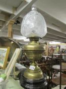 A brass oil lamp with shade and chimney.