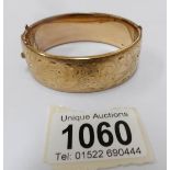 A 9ct gold on a metal core engraved bangle, circa 1970's.