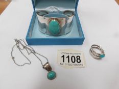A silver turquoise bracelet, ring and pendant.