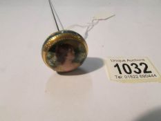 An early 20th century hat pin with portrait of a lady (possibly hand painted).