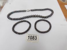 A black Honora graduated pearl necklace and 2 matching bracelets.