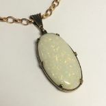 An oval cabochon opal pendant in 9ct gold and on a 9ct gold fancy link chain,