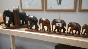 A pair of elephant book ends (trunk a/f) and 6 graduated wooden elephants on stand.