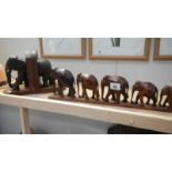 A pair of elephant book ends (trunk a/f) and 6 graduated wooden elephants on stand.