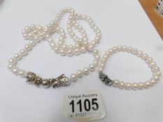 A white pearl necklace with silver dragon fastening (37" long) with a matching bracelet.