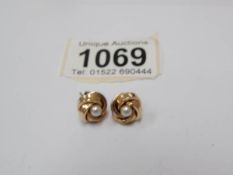 A pair of gold stud earrings set with a pearl.