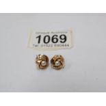 A pair of gold stud earrings set with a pearl.