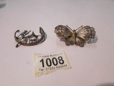 A filigree butterfly brooch marked 800 and a white metal brooch with Chinese figure in boat.