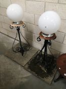 A pair of wrought iron illuminated gate post finials on sand stone bases