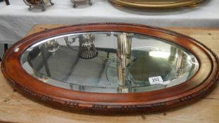 An oval framed bevel edged mirror.