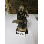 A bronze? figure of a chimpanzee reading.