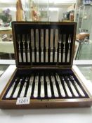 An Edwardian oak cased 24 piece set of fruit cutlery with mother of pearl handles and silver
