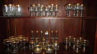 2 shelves of gold decorated glass ware.